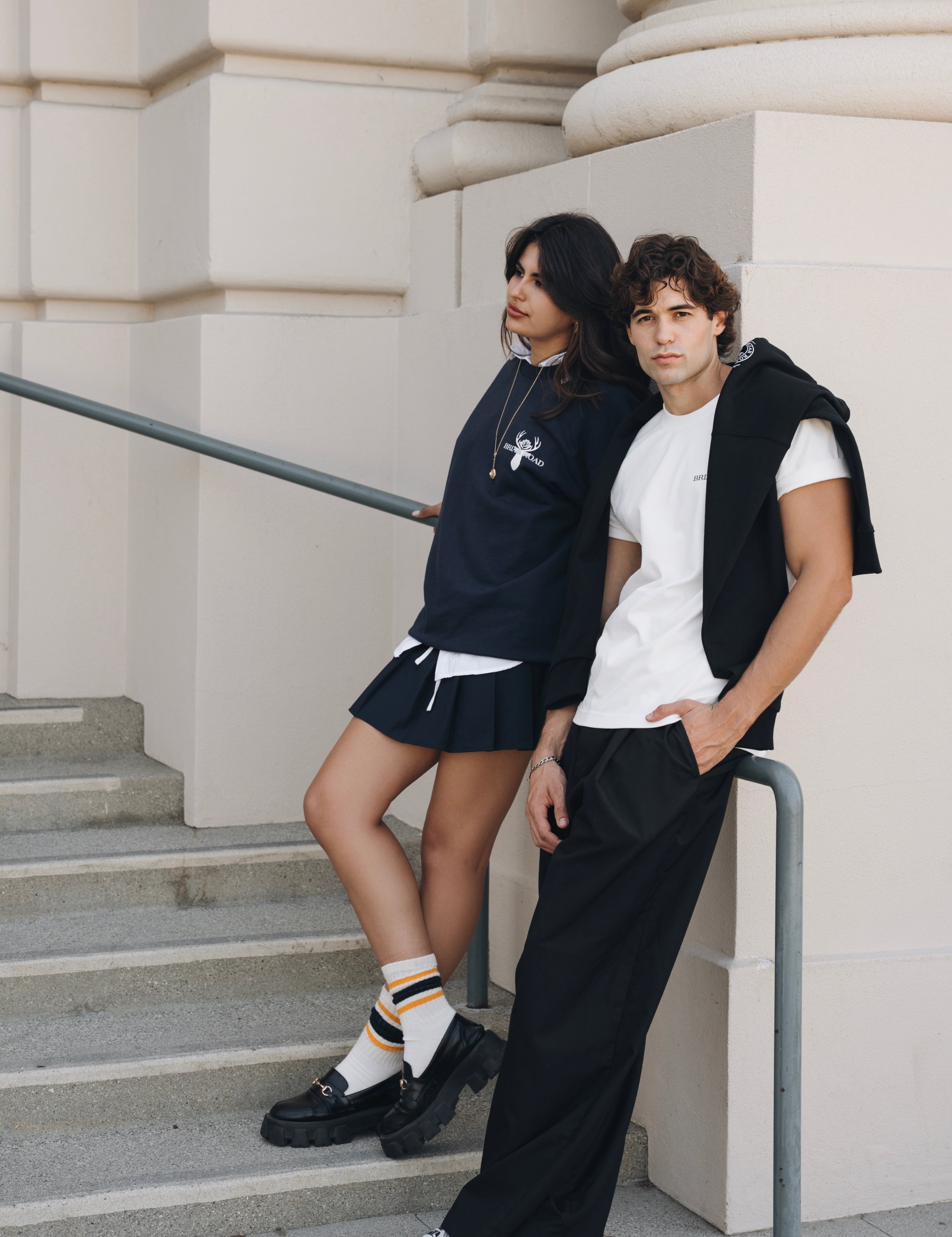Couple wearing matching crewnecks, styled in a preppy, urban manner 