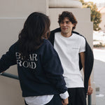 Woman wearing long sleeved blue crewneck and skirt. Man wearing white short sleeved crewneck