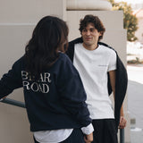 Woman wearing long sleeved blue crewneck and skirt. Man wearing white short sleeved crewneck
