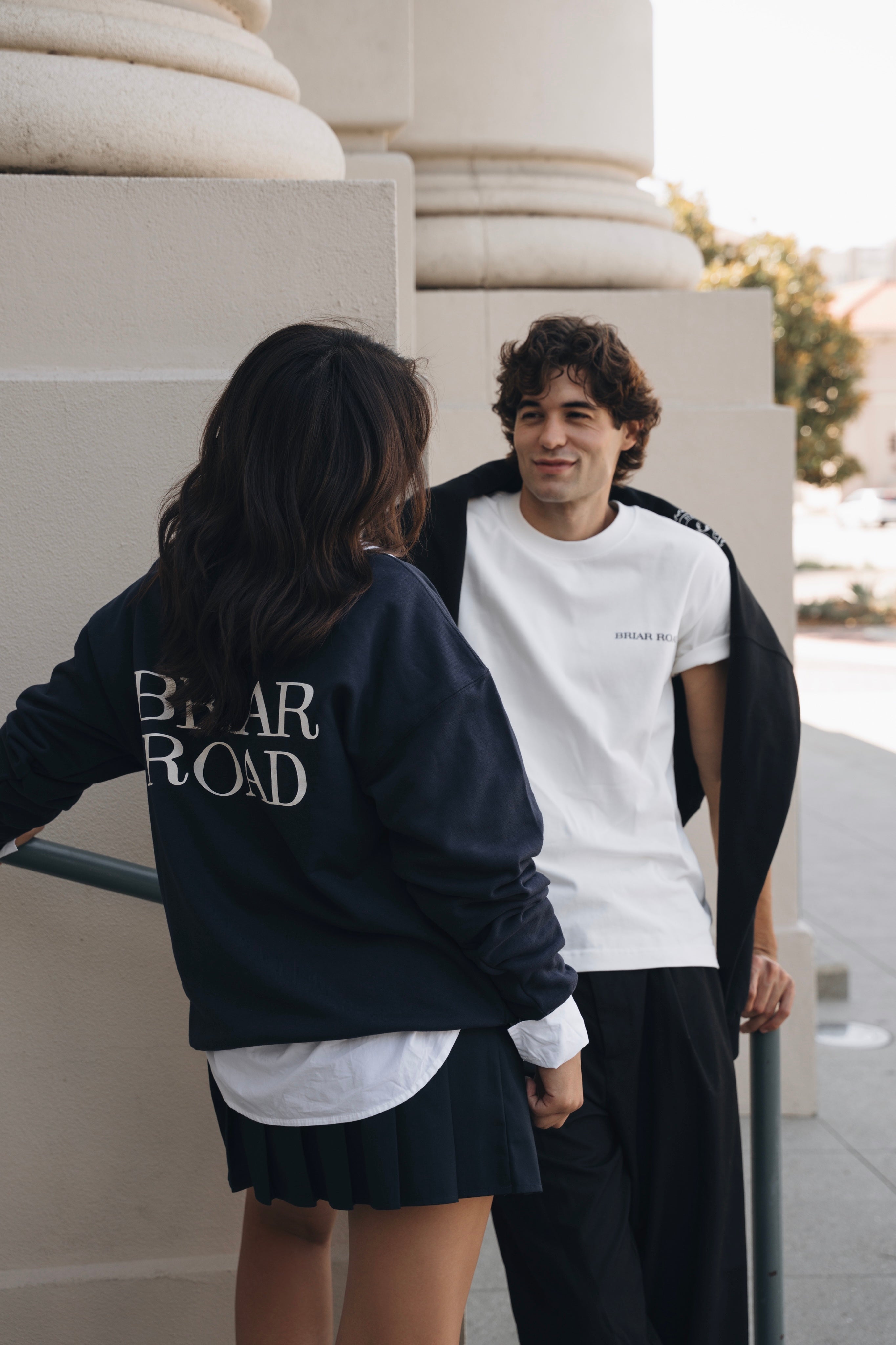 Woman wearing long sleeved blue crewneck and skirt. Man wearing white short sleeved crewneck