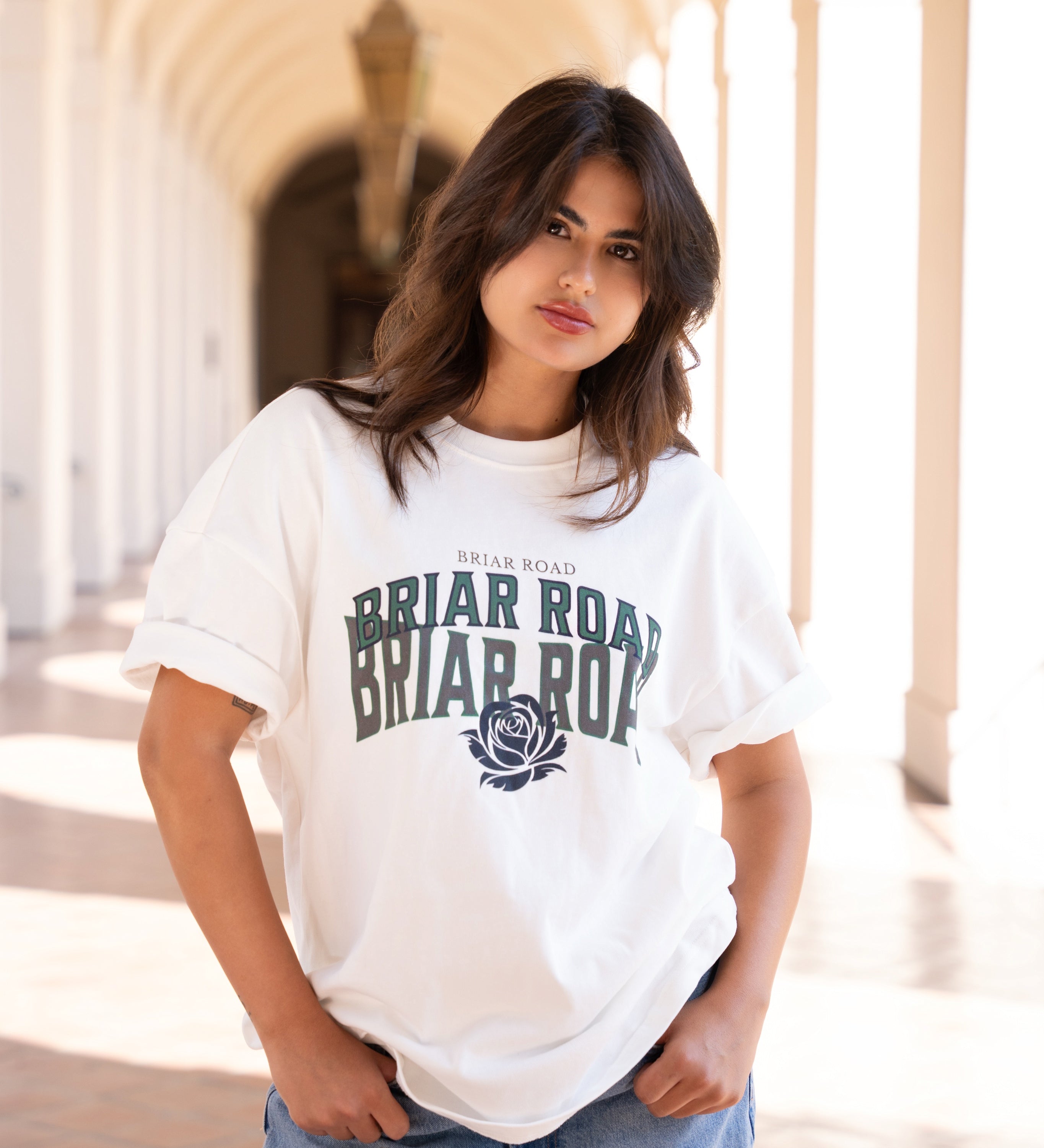 Woman wearing white oversized crewneck with Briar Road branding