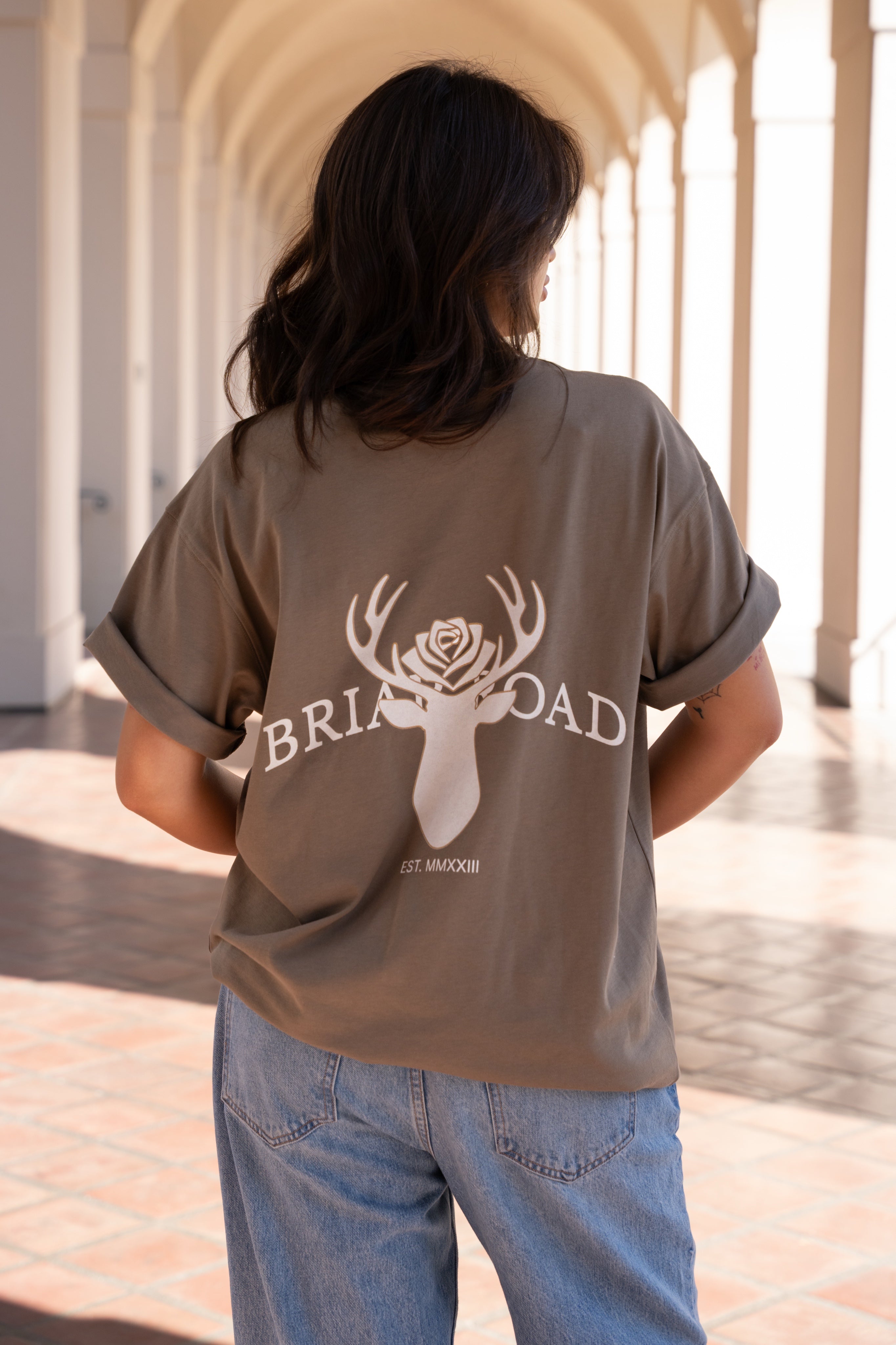 Woman wearing brown oversized crewneck sweatshirt featuring Briar Road logo